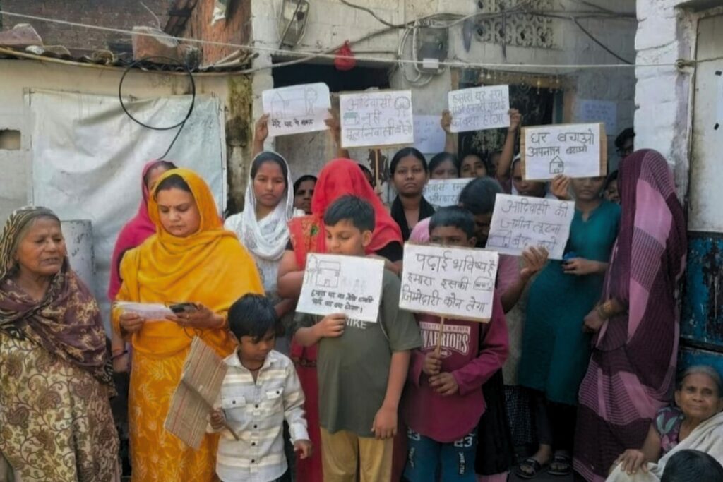 घरों को तोड़ने के आदेश का विरोध करती बस्ती के लोग