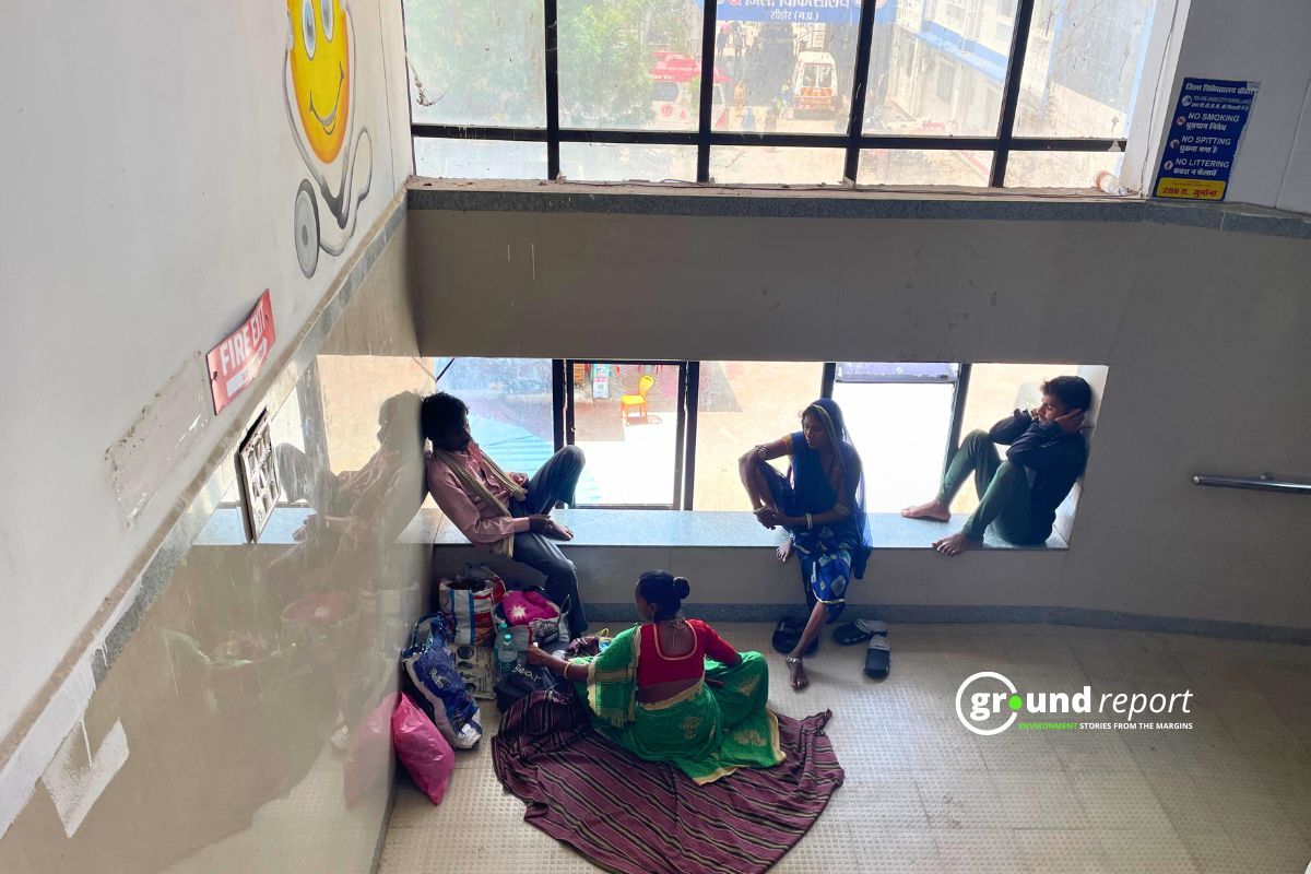 Outside the children's ward of Sehore Hospital, patients and their relatives are sitting near the window to escape the heat.