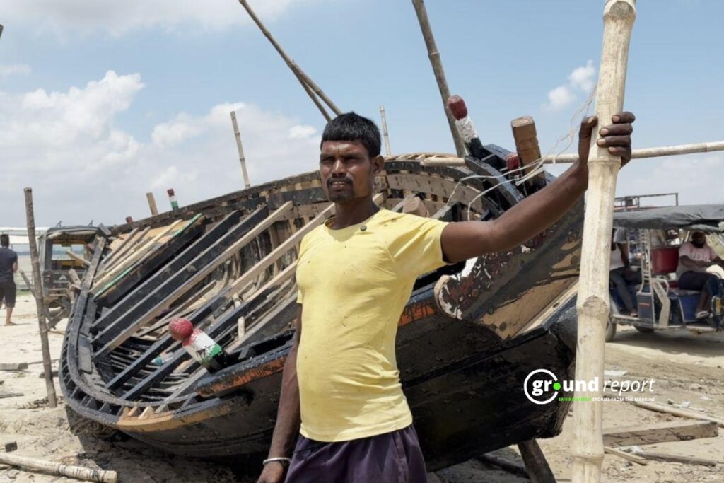 Rakesh Kumar, a fisherman and a boatman, stands at the bank of the Ganga, painting his new wooden boat