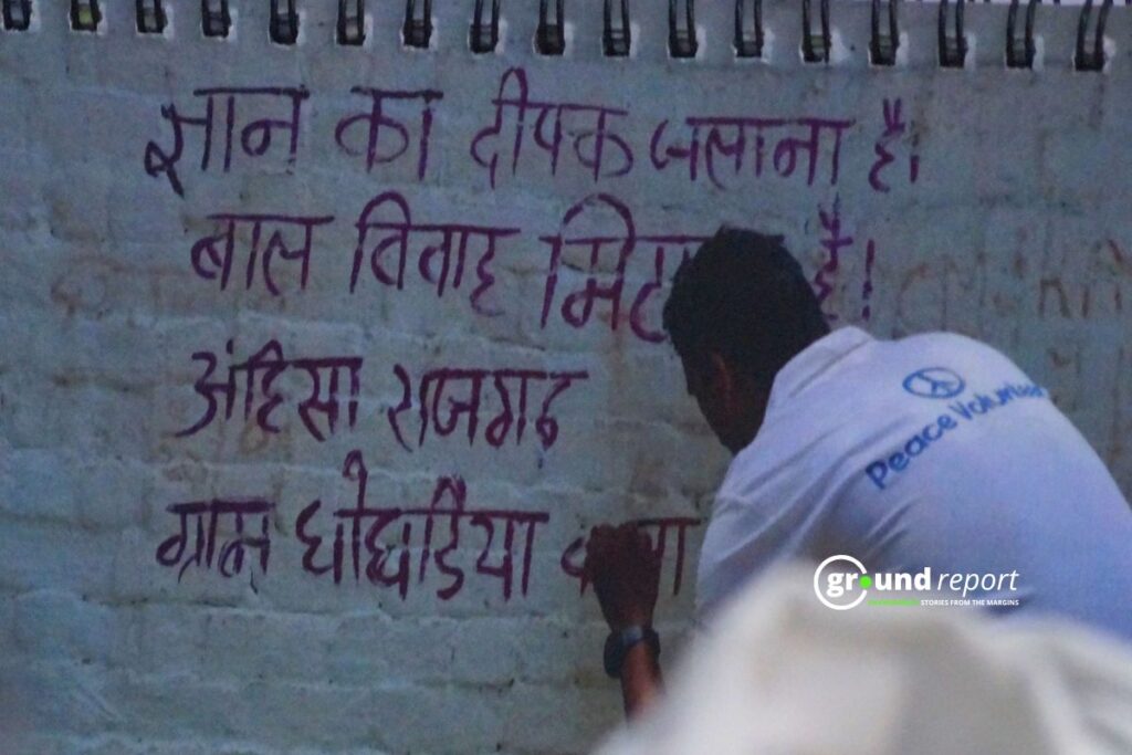 An Ahimsa Welfare Society volunteer writes an anti-child marriage message on a village wall.