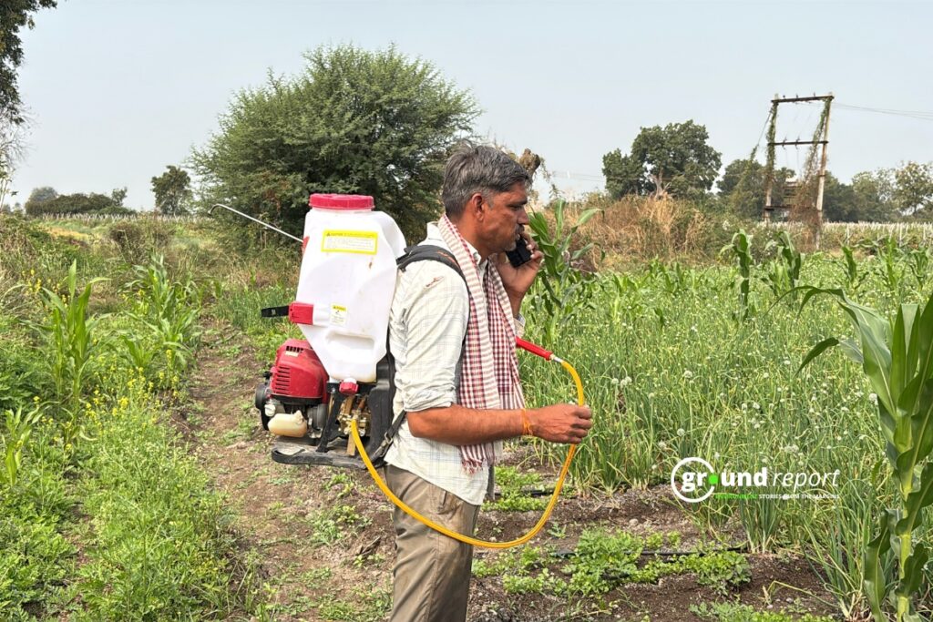 A farmer carries a pesticide sprayer through his crop field in India.
