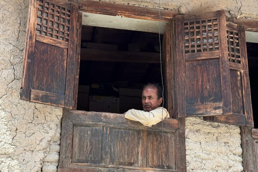 A man looks out from a window in old Srinagar. Photo credit: Wahid Bhat/Ground Report