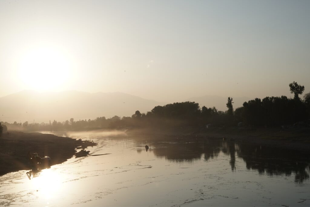 The sun rises over a Kashmir river running low. As the region warms, water levels like these are becoming harder to rely on. Photo credit: Wahid Bhat/Ground Report