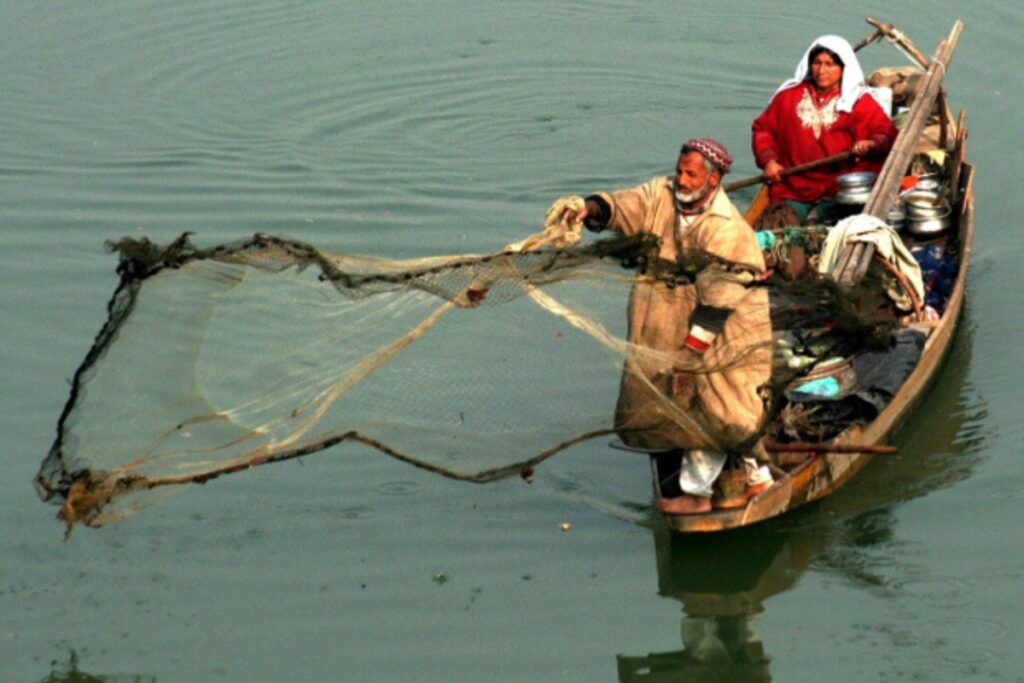 A fisherman pulls in his net as another family member sits in the boat