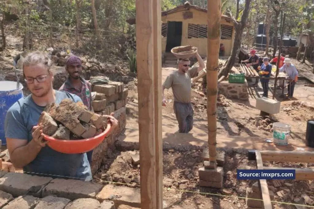 Volunteers and local workers engaged in the construction of a mud house