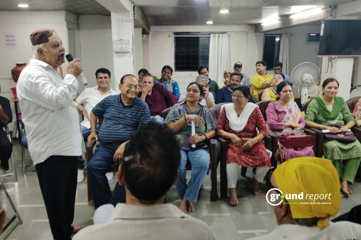 Community members sit together in Indore, listening to Kishore Kodwani as he leads a discussion on local disputes and civic issues.