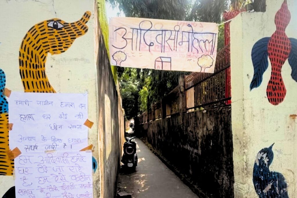 आदिवासी बस्ती की गली की दीवारों पर कुछ ऐसे पोस्टर्स लगे हुए हैं