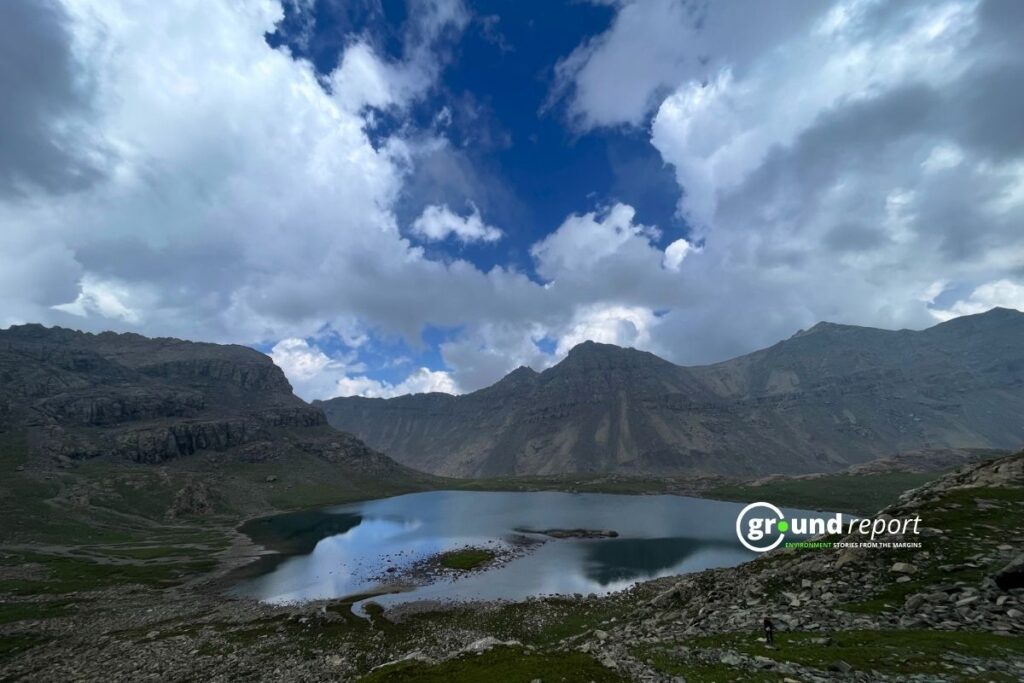 A glacial lake in Kashmir reflects the surrounding mountains. The lake is held back by walls of loose rock and debris that could collapse without warning.