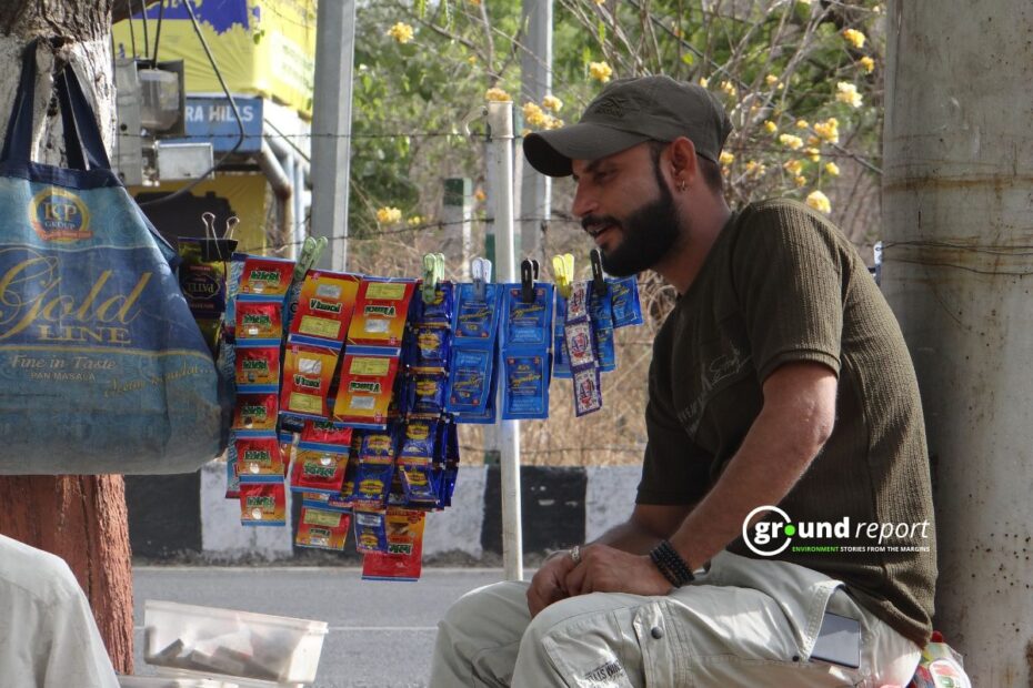 A vendor sits beside rows of gutkha and pan masala pouches at a street stall. Enforcement of India's gutkha ban remains weak across most states.