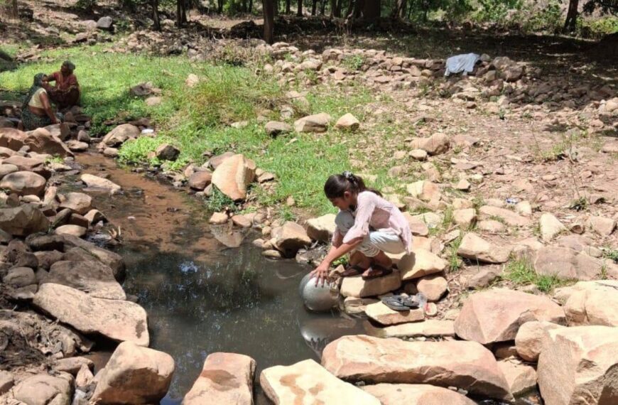 Rekha fills a vessel from a muddy spring in Chitrakoot, where many families depend on distant water sources for daily use.